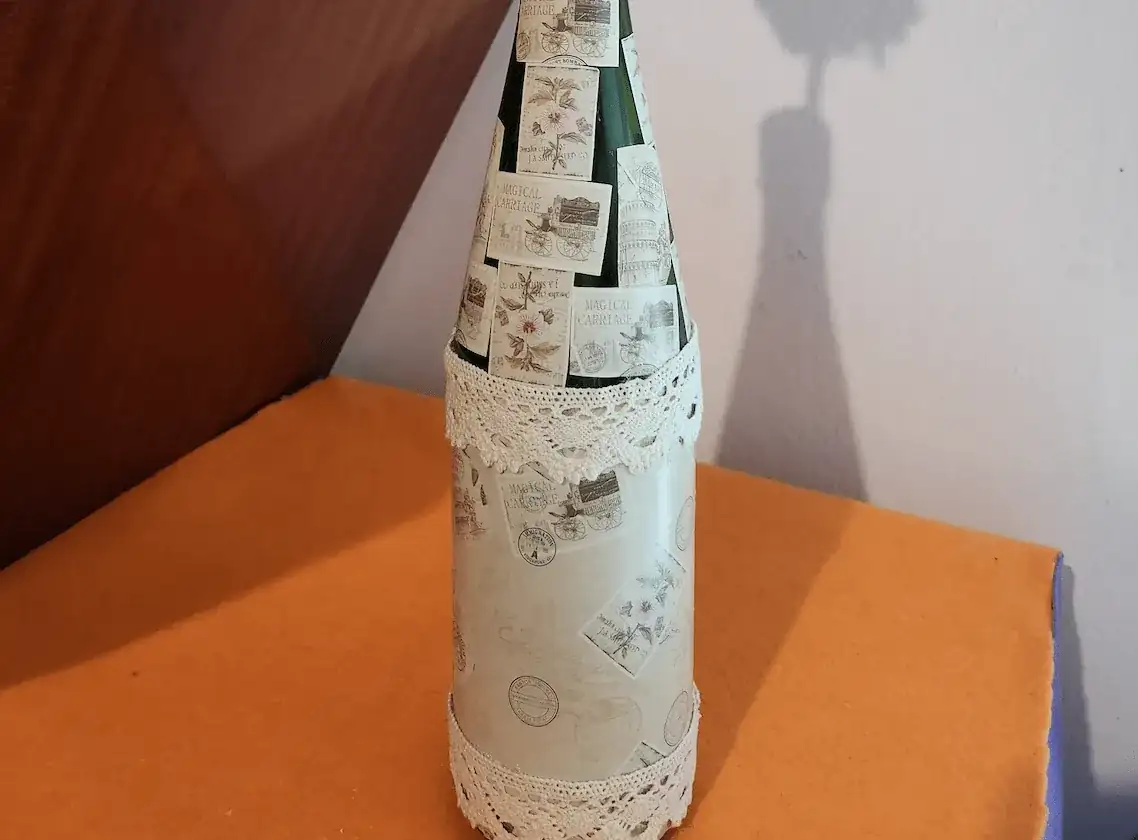 Botella decorada con encaje y pegatinas y flor rosa